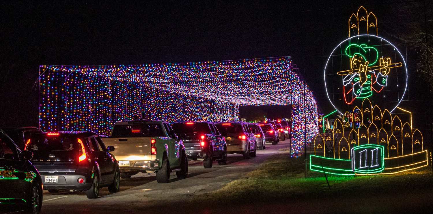Cars moving slowly through a lit Christmas tunnel