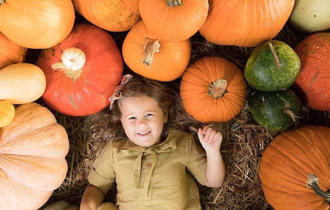 A child lying among heirloom pumpkins in the patch